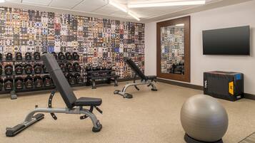 A gym with weightlifting equipment, exercise balls, and a television.