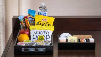 A tray with snacks and condiments including Lay's Baked chips, Skinny Pop white cheddar, and a bottle of water.