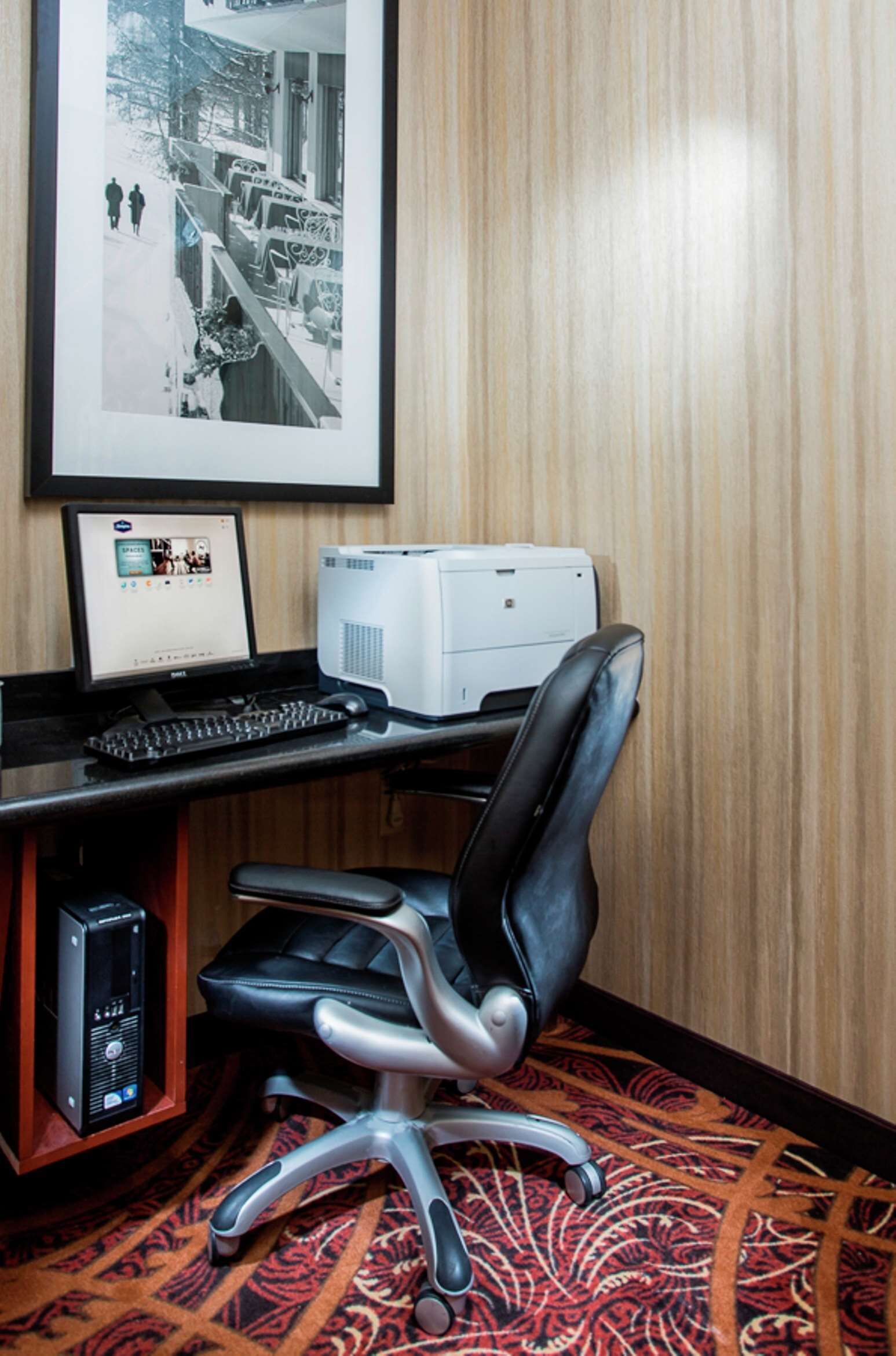 A computer desk with a monitor, keyboard, and printer.