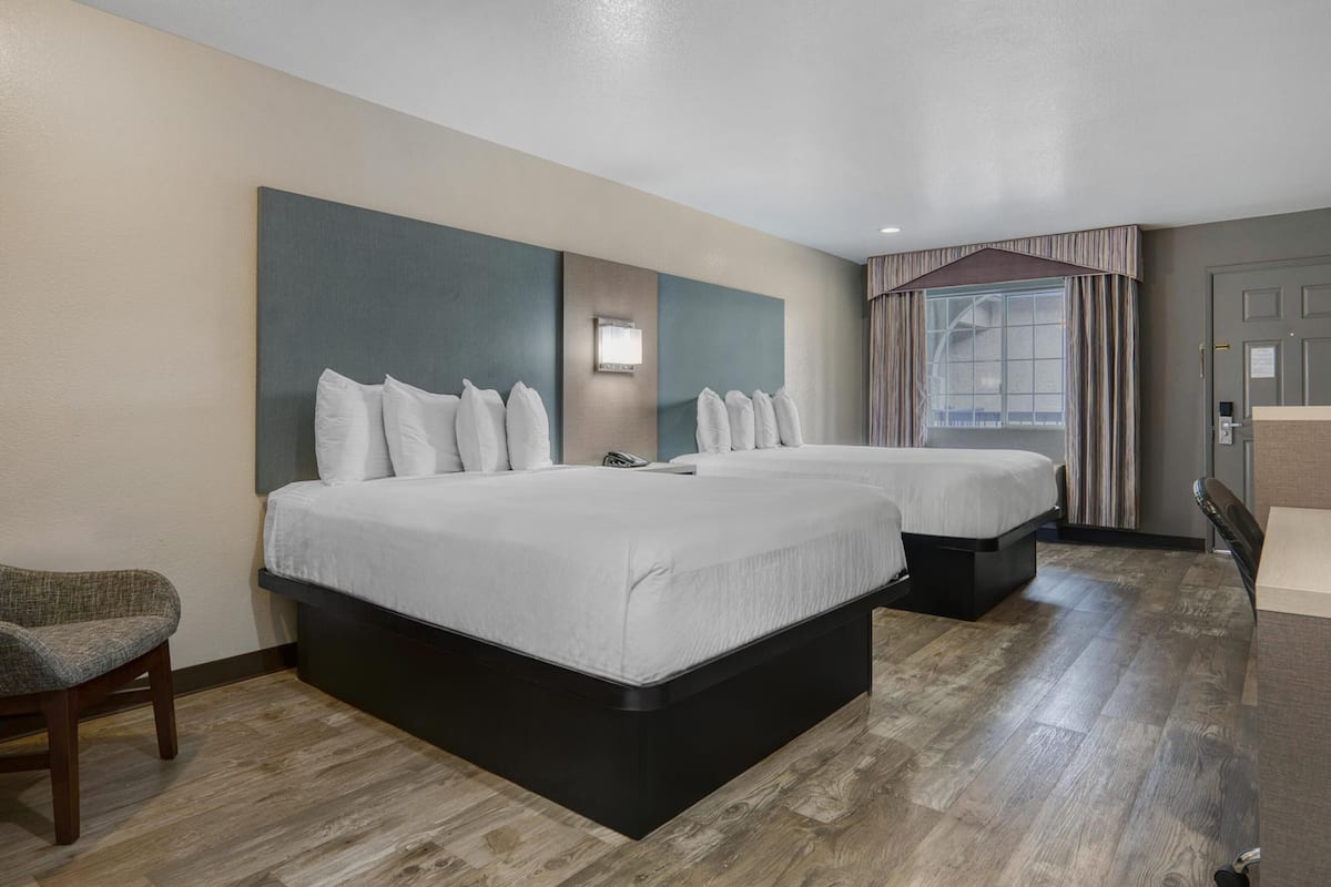 Een hotelkamer met twee bedden, een zithoek en een groot raam met gordijnen.
