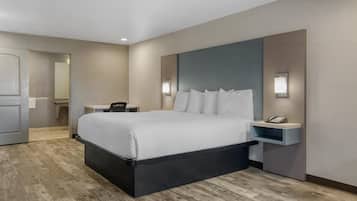 Quarto de hotel moderno com uma cama grande, mesas de cabeceira, uma escrivaninha e um espelho.