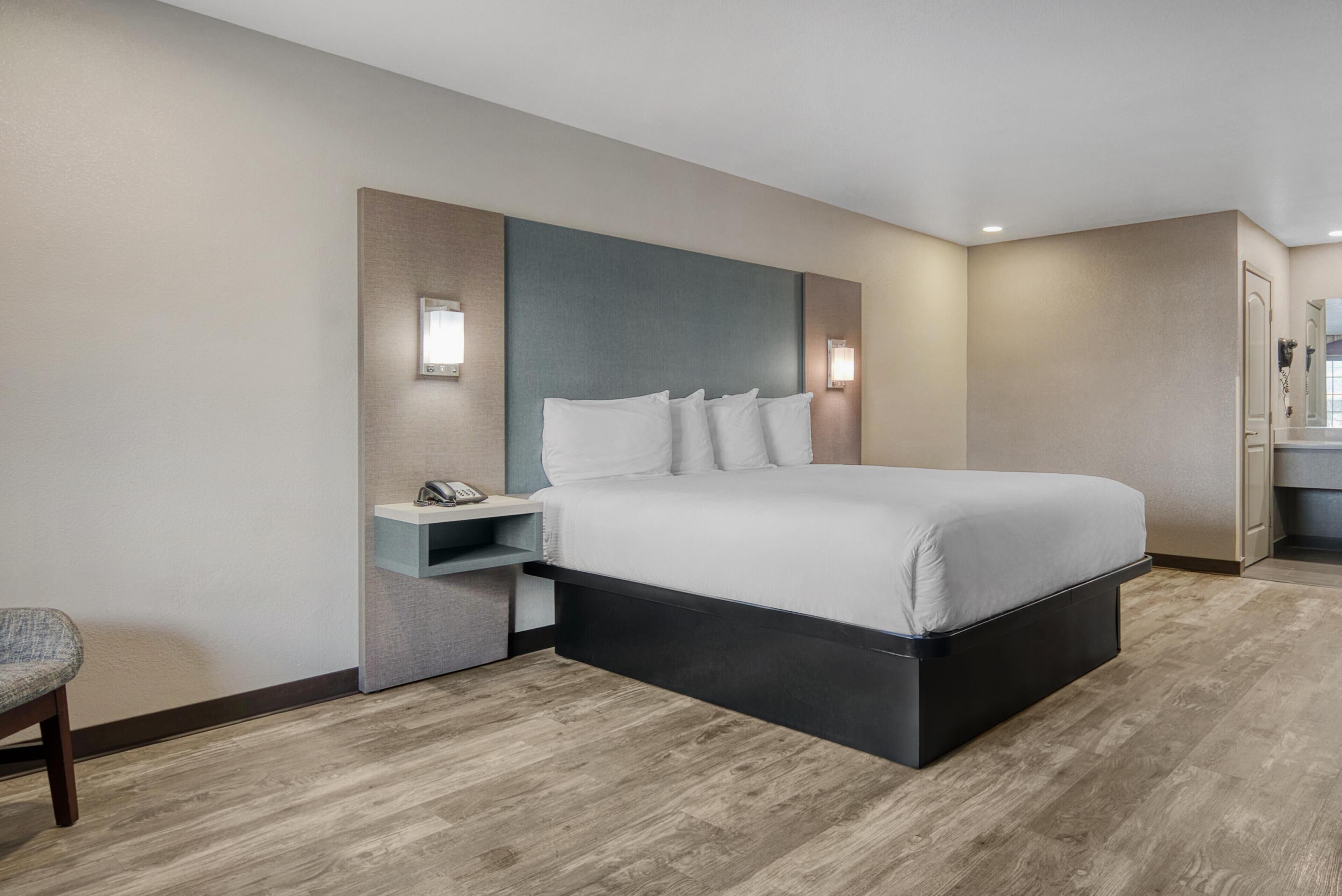 Een moderne hotelkamer met een groot bed, een nachtkastje met een telefoon en een klein zithoekje.