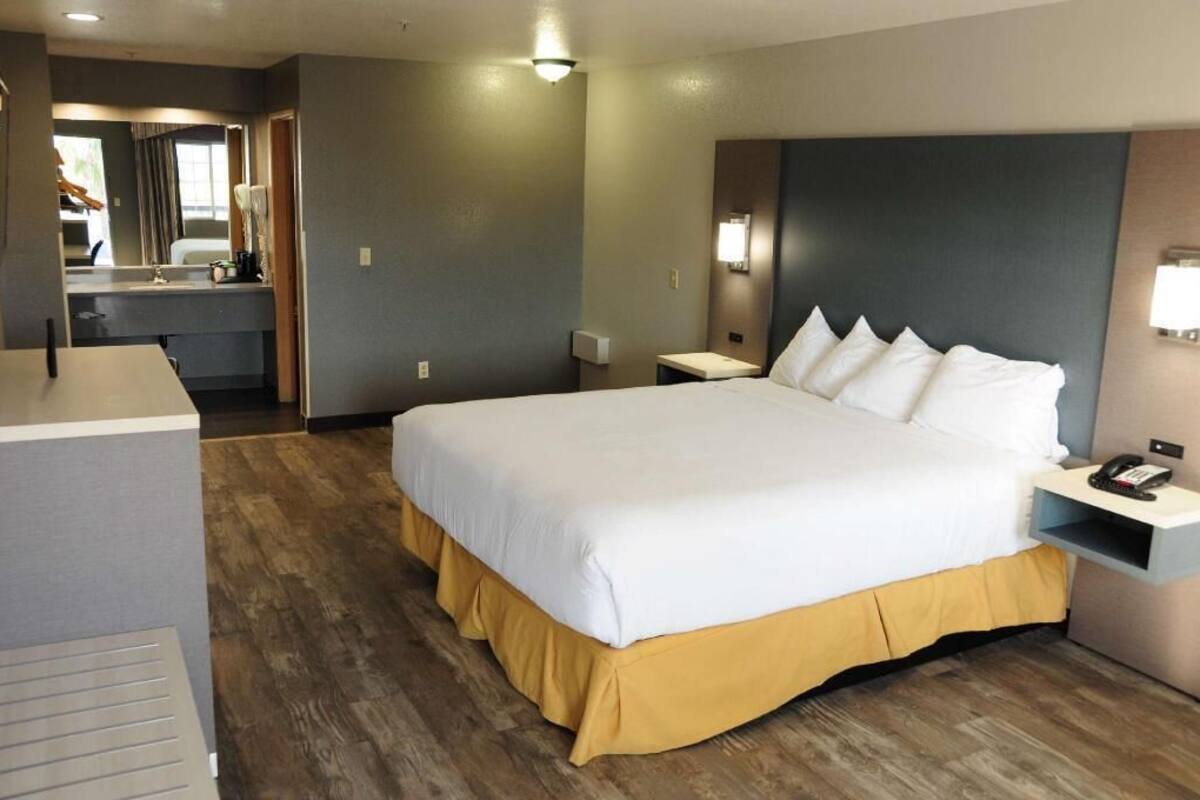 Hotelkamer met een groot bed, nachtkastje, spiegel en een klein badgedeelte.