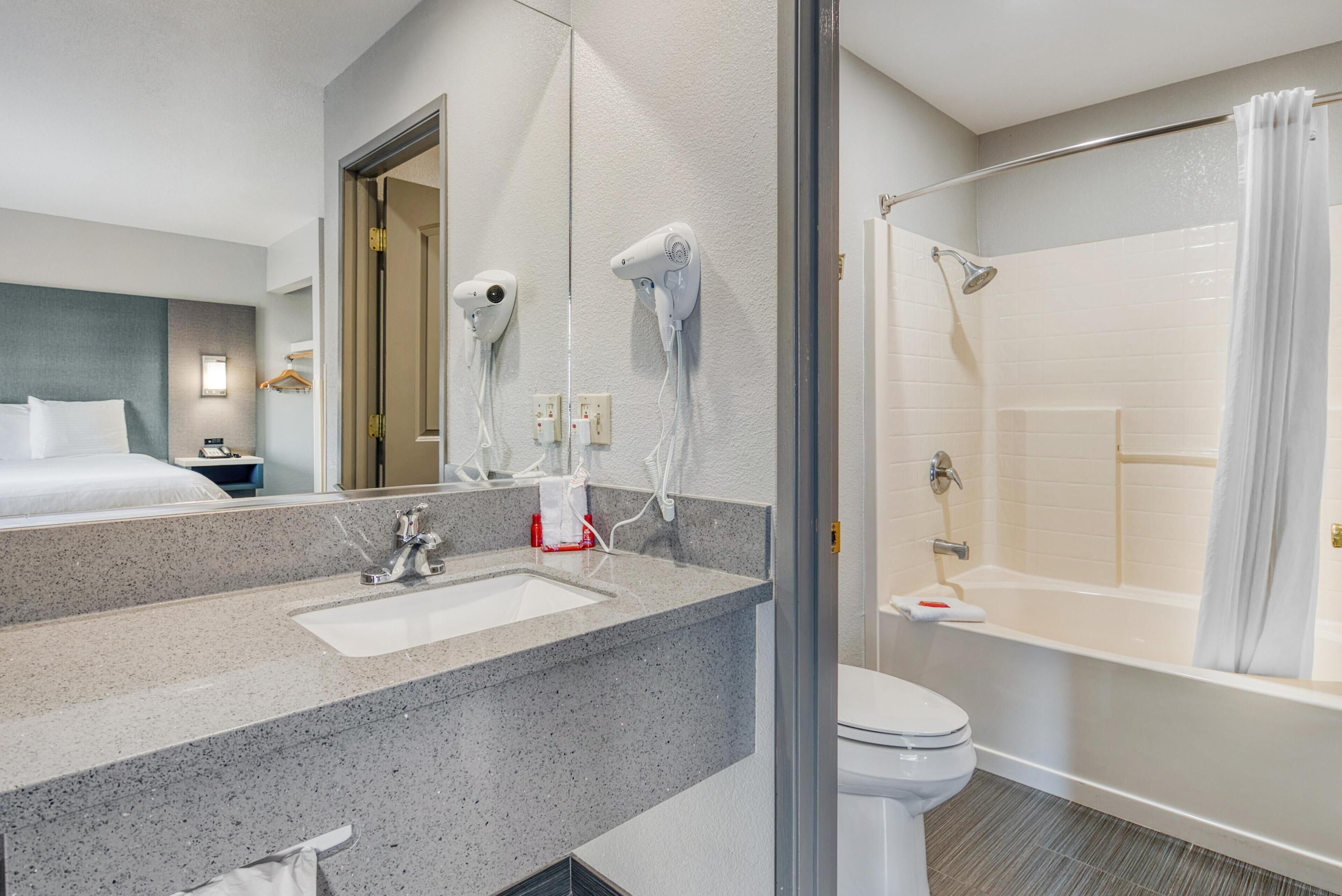 A hotel bathroom with a sink, toilet, and shower.