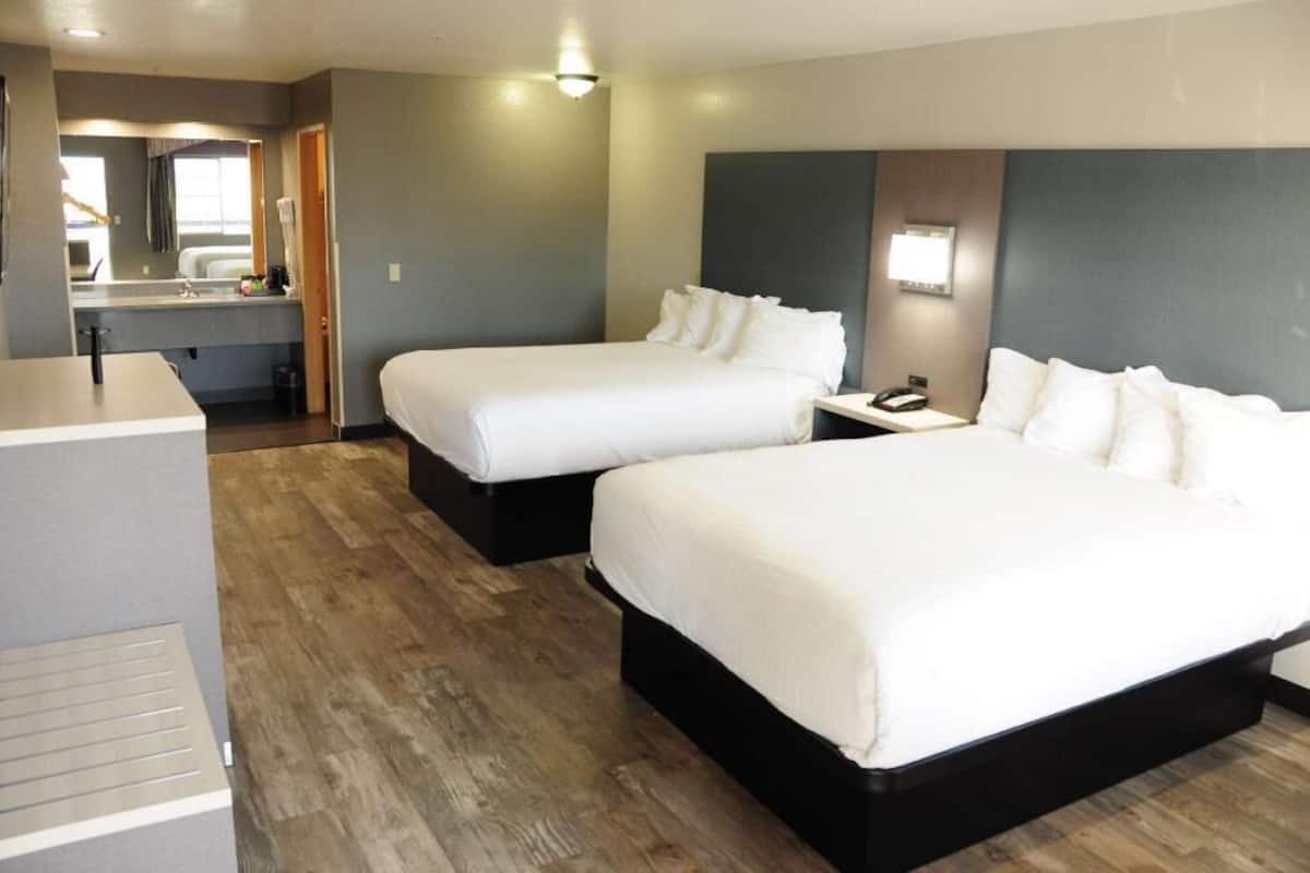 Een hotelkamer met twee bedden, een bureau, een spiegel en een kleine badkamer.