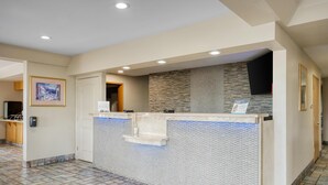 A reception area with a tiled floor, a reception desk, a wall-mounted TV, and a framed picture on the wall.
