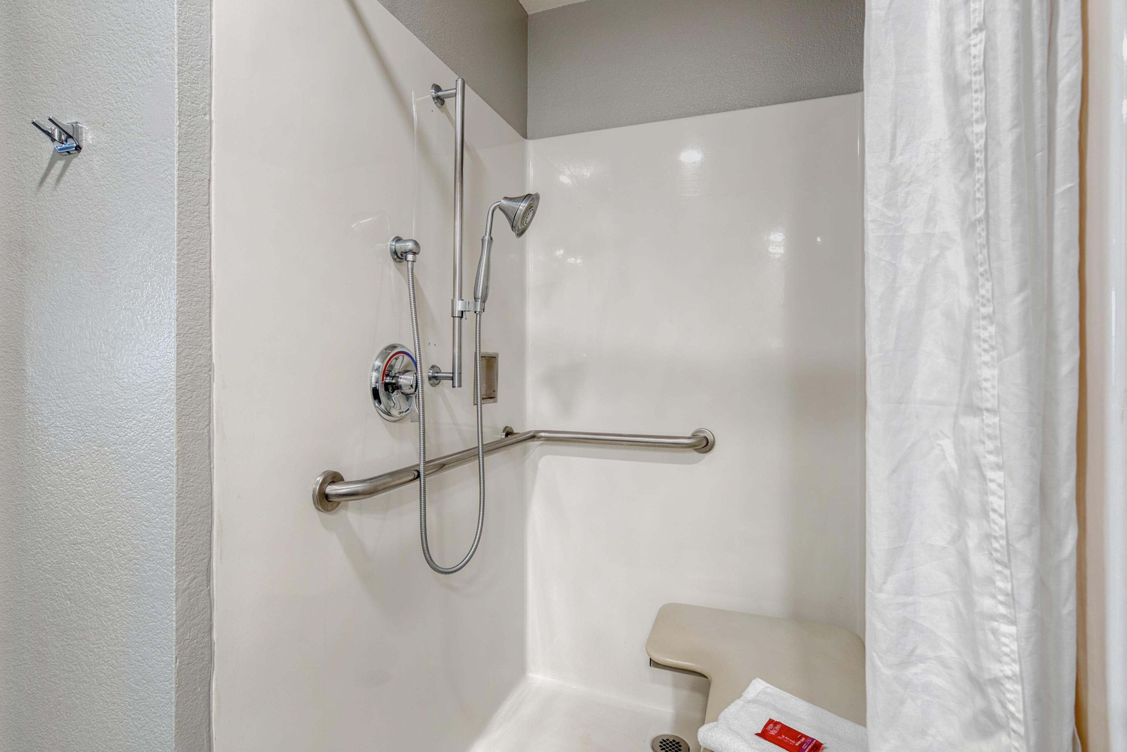 A bathroom with a shower, grab bar, and toilet.