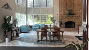 A spacious living area with a fireplace, large windows, and a dining table. - Days Inn by Wyndham Lisbon (Lisbon)