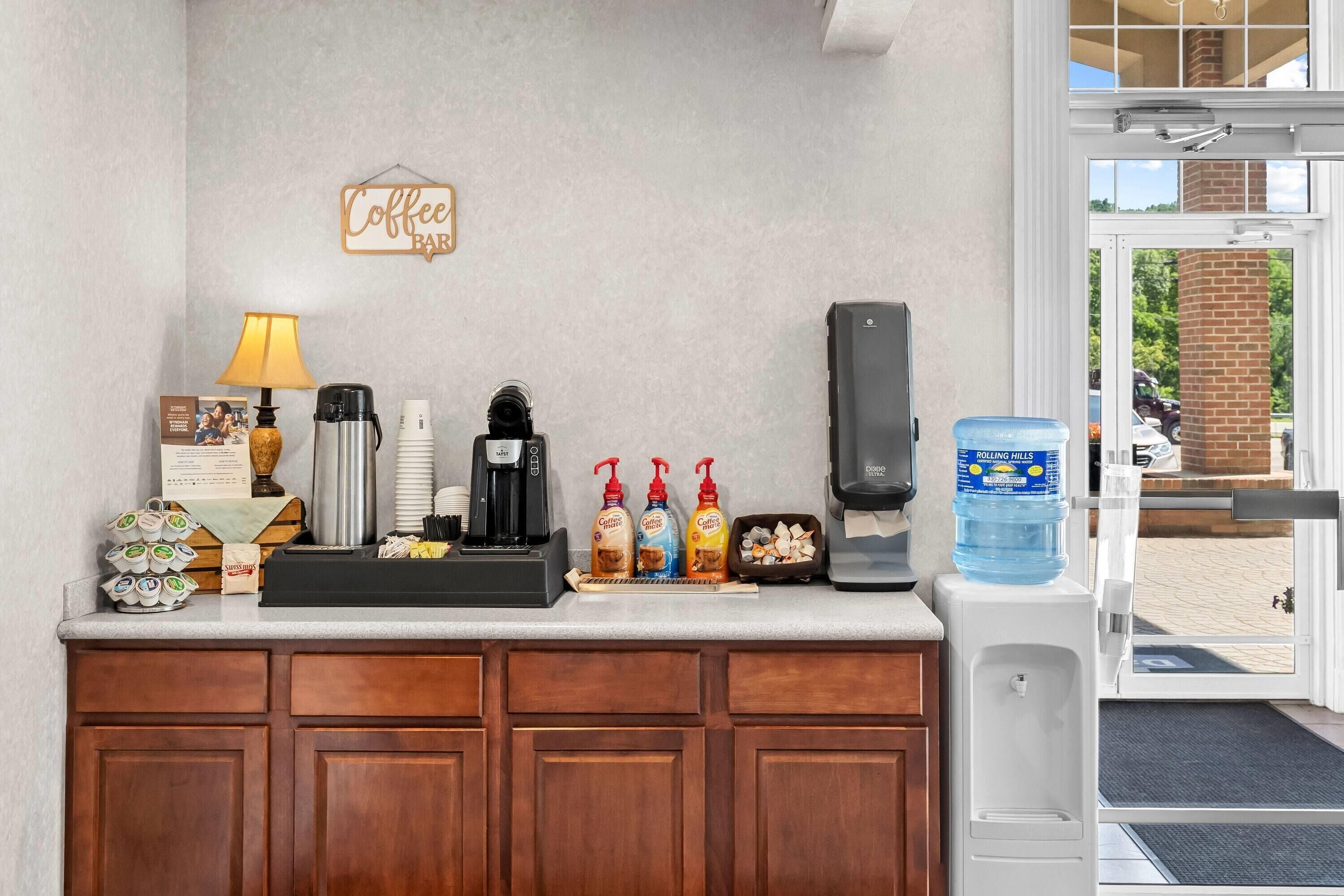 A coffee station with a coffee maker, cups, and a water dispenser.