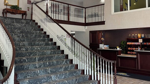 A grand staircase with marble steps and white balusters, leading to a second floor. A chandelier hangs from the ceiling, and a reception desk is visible on the second floor. - Days Inn by Wyndham Lisbon (Lisbon)