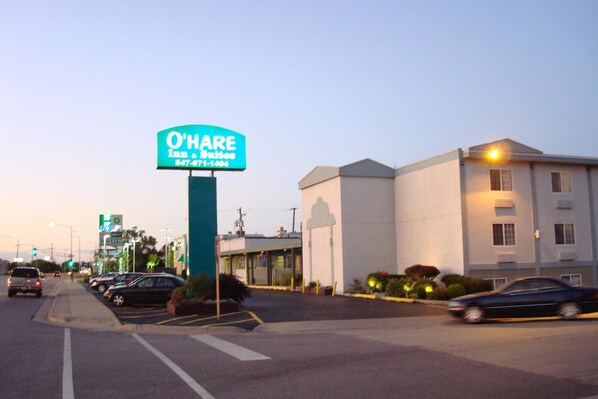 Une enseigne d’hôtel pour l’O’Hare Inn & Suites, avec un parking et des bâtiments en arrière-plan.