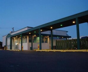 A single-story building with a covered entrance and a fenced parking area.