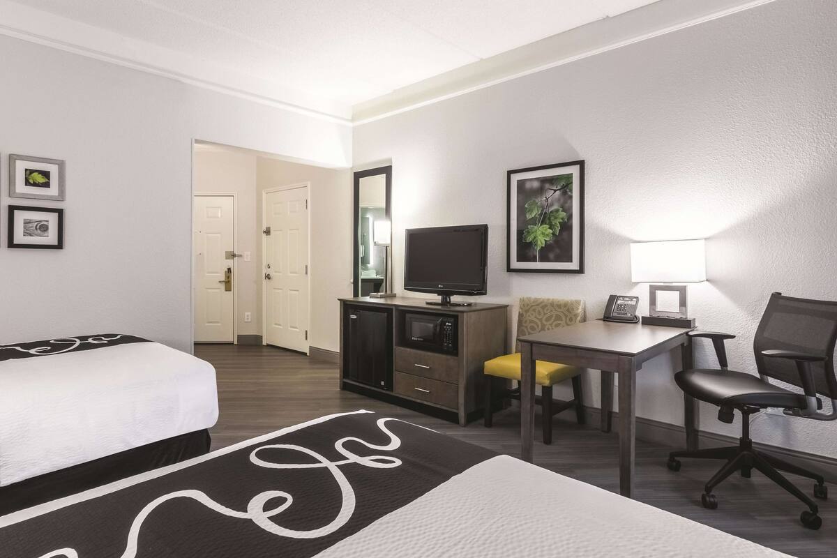 Une chambre d’hôtel avec un lit, un bureau et une chaise, une télévision et une lampe.