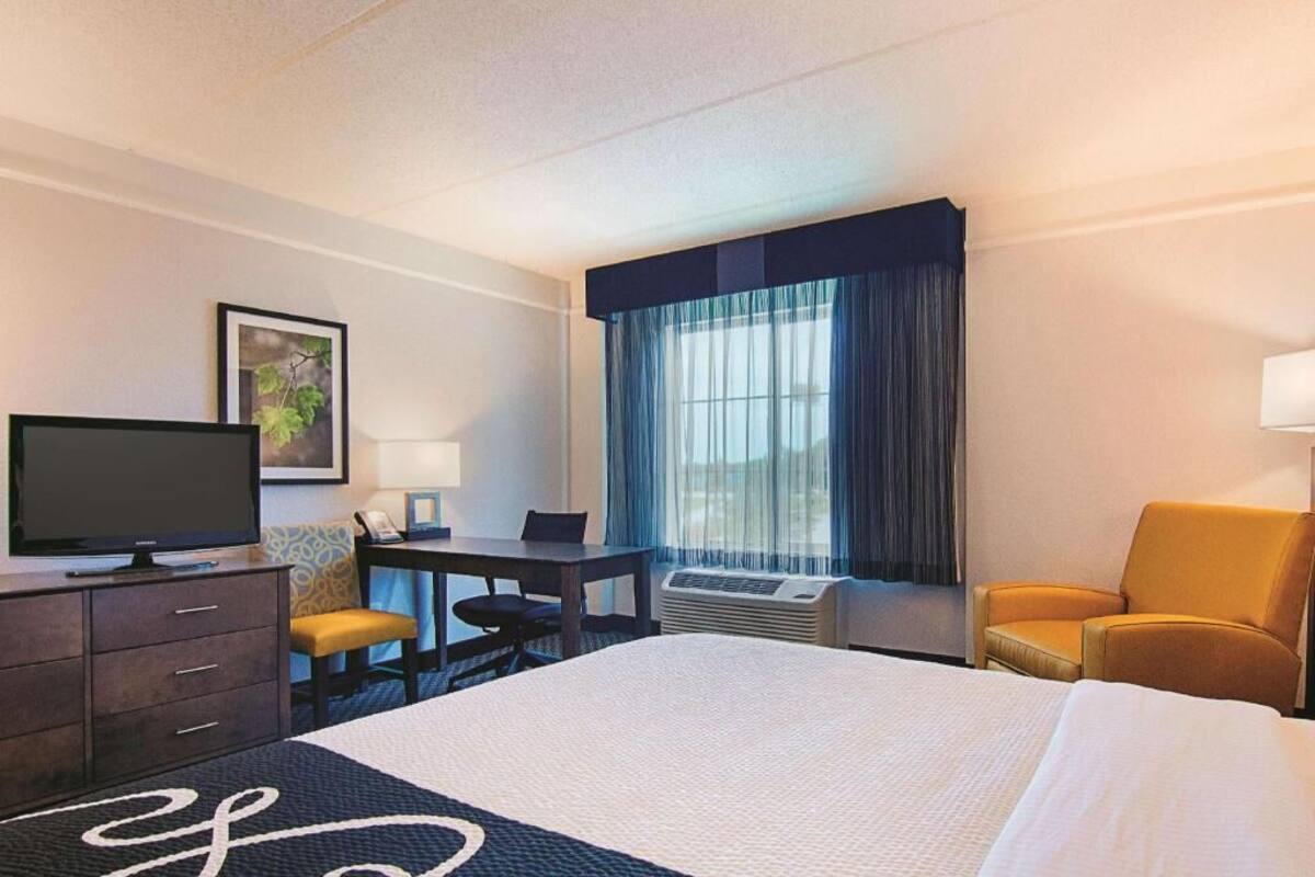 Une chambre d’hôtel équipée d’un lit, d’un bureau, d’une chaise, d’une télévision et d’une fenêtre avec des rideaux.