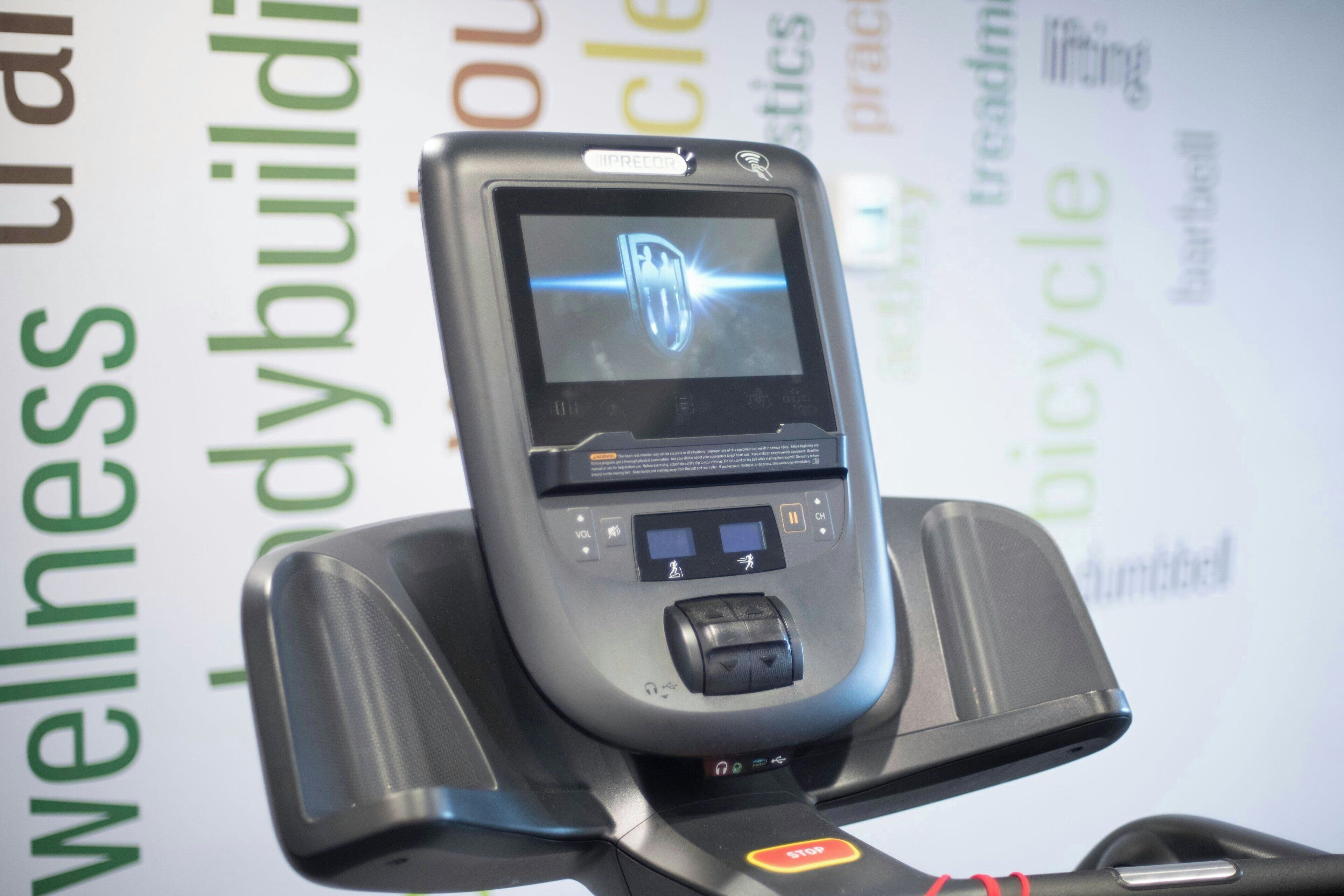 A mobile phone charging on a stand with a visible logo on the screen.