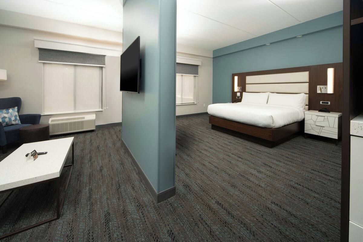 A hotel room with a bed, a desk, a chair, a TV, and a nightstand.
