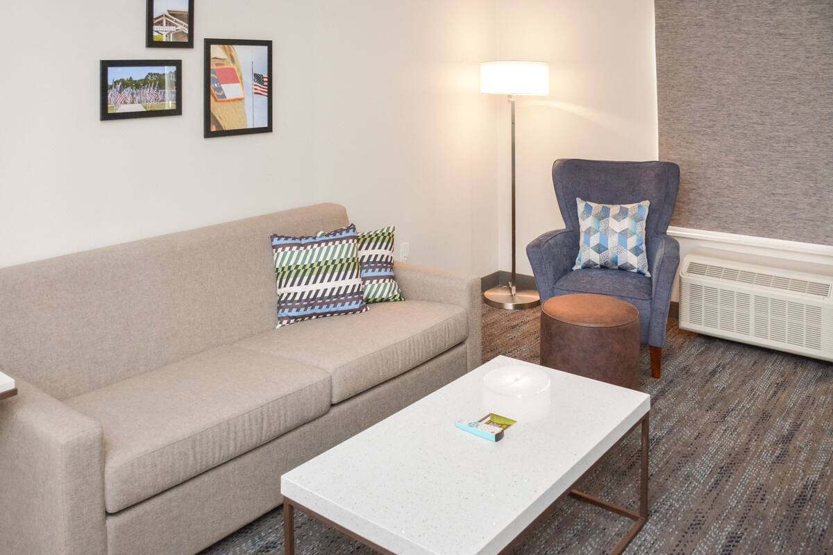 A living room with a beige sofa, a white coffee table, a blue armchair, and a floor lamp.