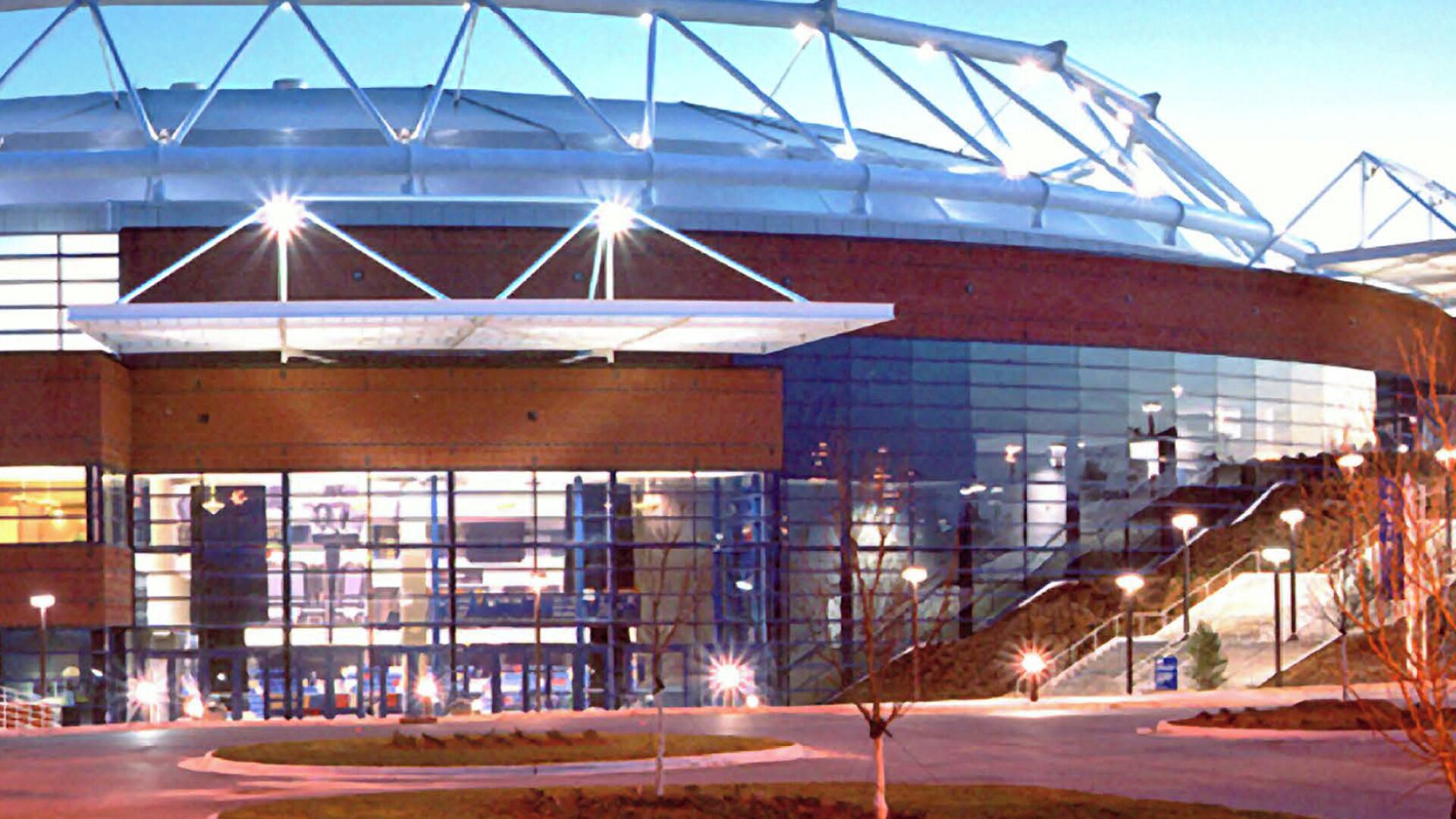 A modern building with a glass facade, a covered entrance, and a staircase leading to the upper levels.