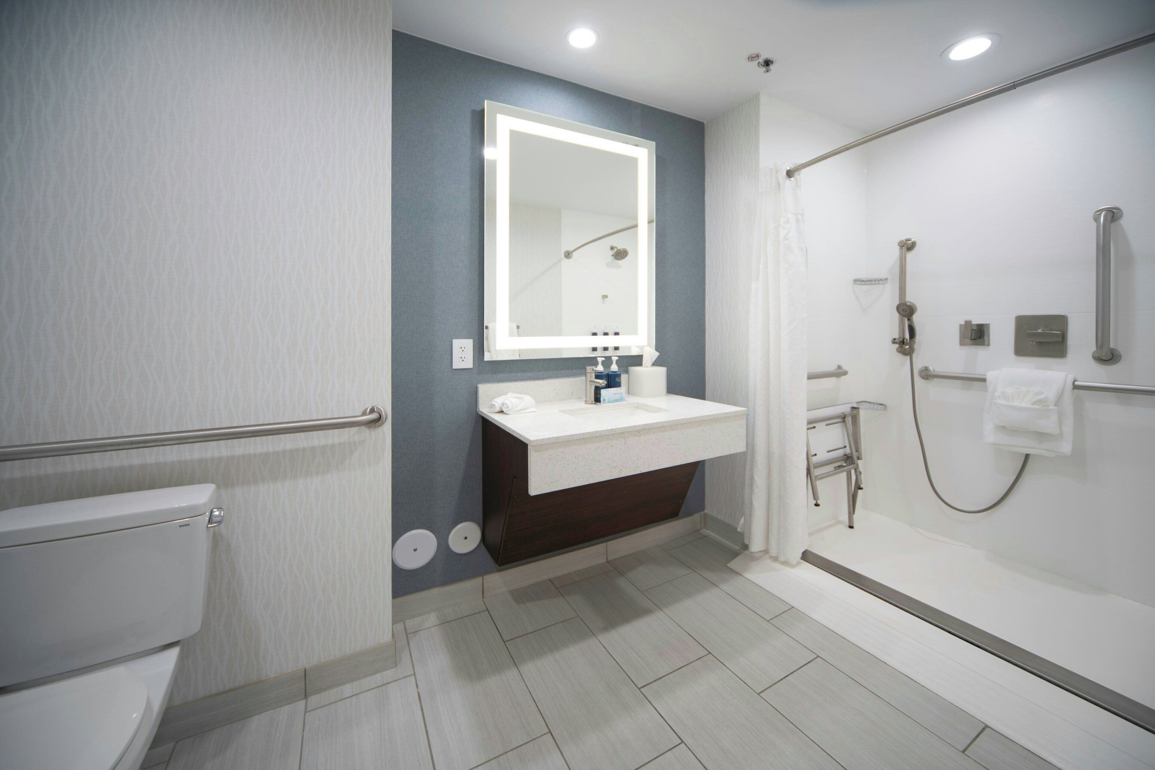 A modern bathroom with a toilet, sink, mirror, and shower.