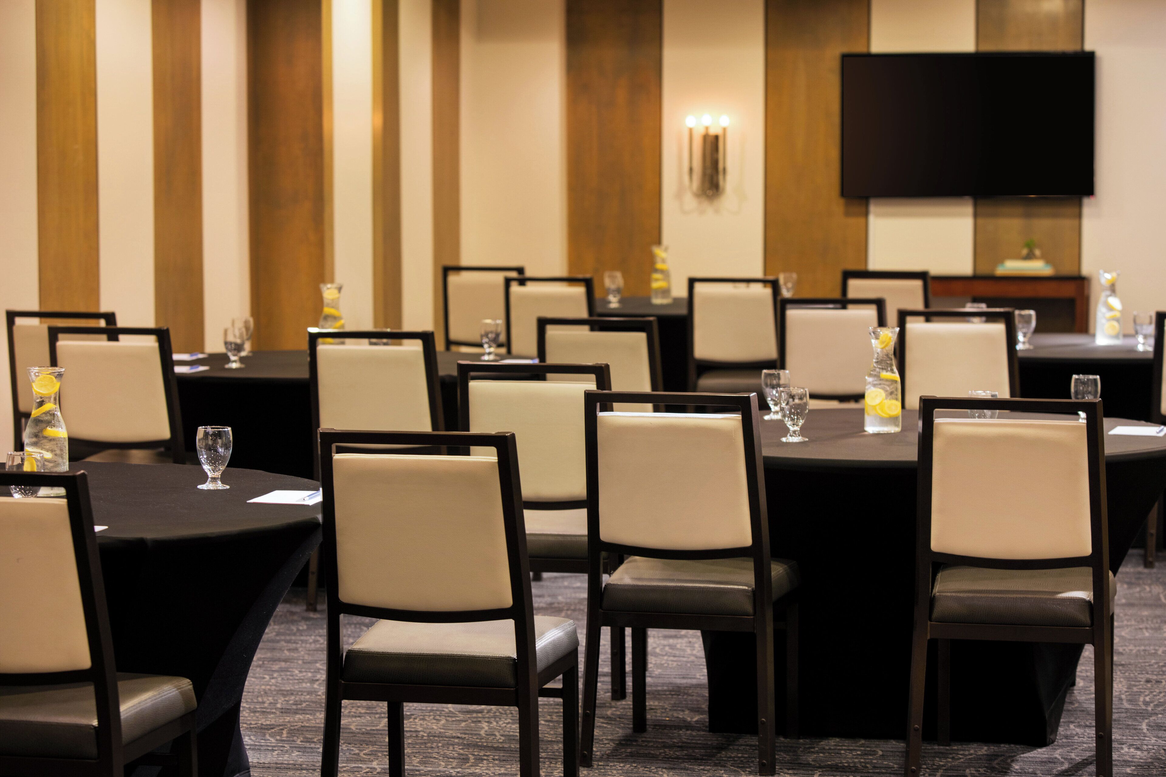 A conference room with multiple tables and chairs, equipped with water bottles and glasses.