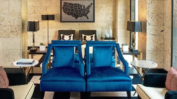 A modern living room with two blue armchairs, a coffee table, a side table with a book, and a wall-mounted map.