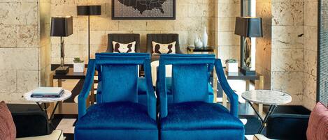 A modern living room with two blue armchairs, a coffee table, a side table with a book, and a wall-mounted map.