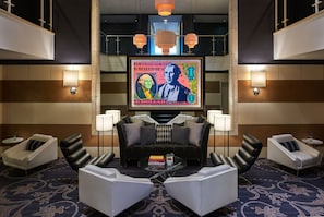 A lobby with a modern design, featuring a sofa, armchairs, a coffee table, and a large framed artwork on the wall. - Kimpton George Hotel by IHG (Washington)