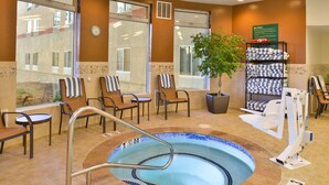 A spa area with a hot tub, chairs, a plant, and a towel rack. - Hilton Garden Inn - Flagstaff (Flagstaff)