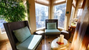 A room with wicker furniture, a large potted plant, and a view of the outdoors. - Hilton Garden Inn - Flagstaff (Flagstaff)