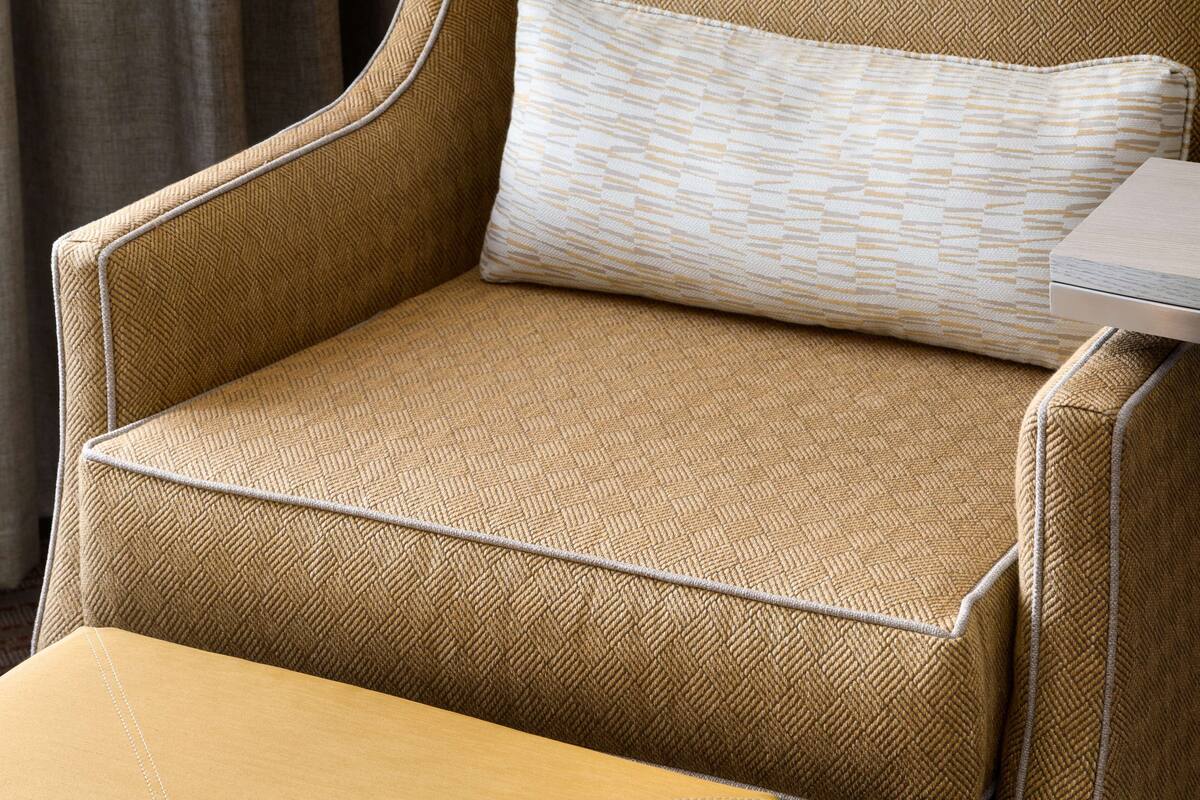 A chair with a textured fabric and a patterned pillow.