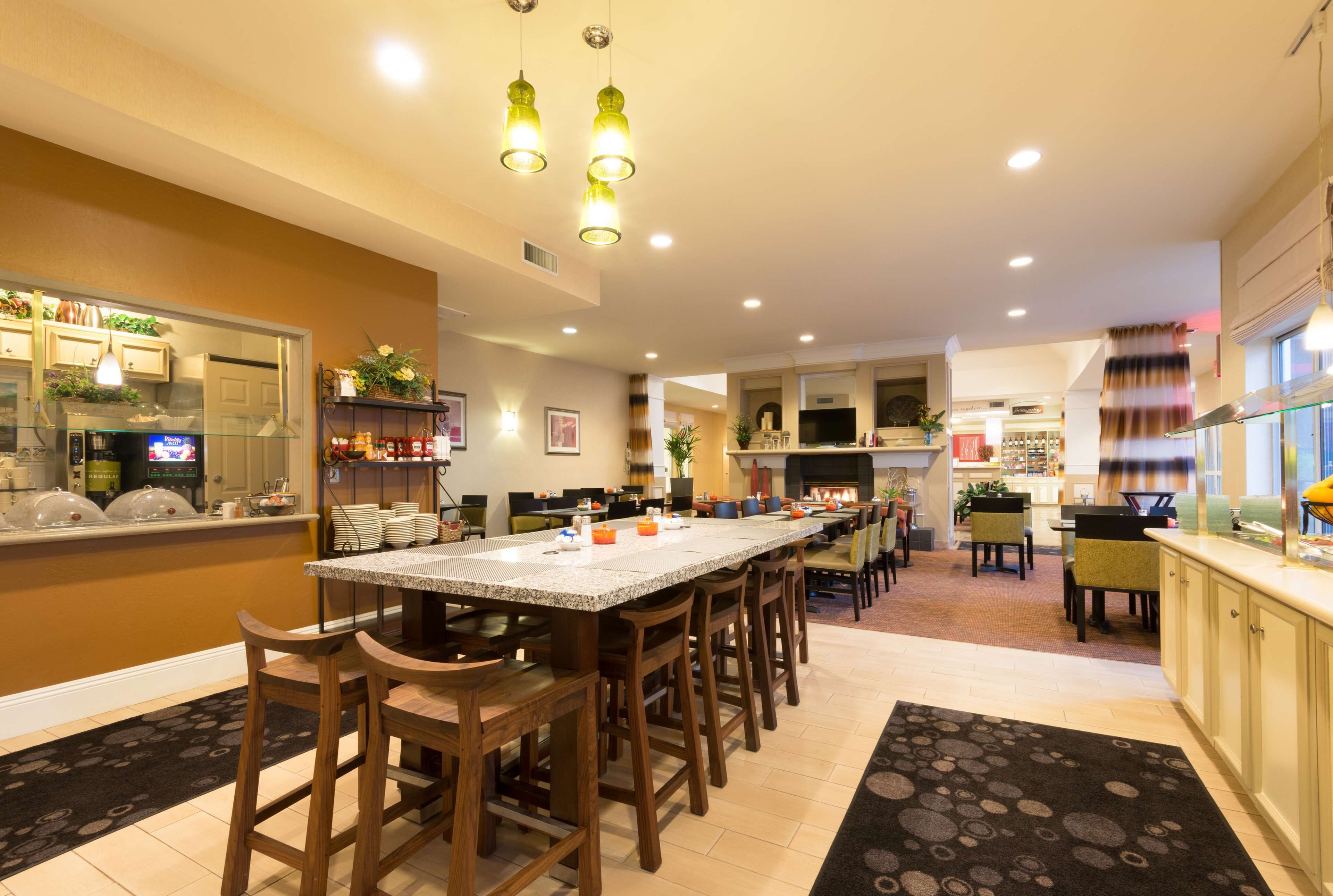 A spacious kitchen with a long island, wooden chairs, and pendant lighting.