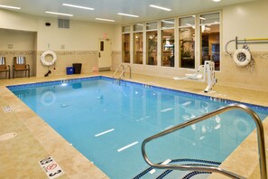 An indoor swimming pool with clear water, a lifebuoy, and a pool ladder.