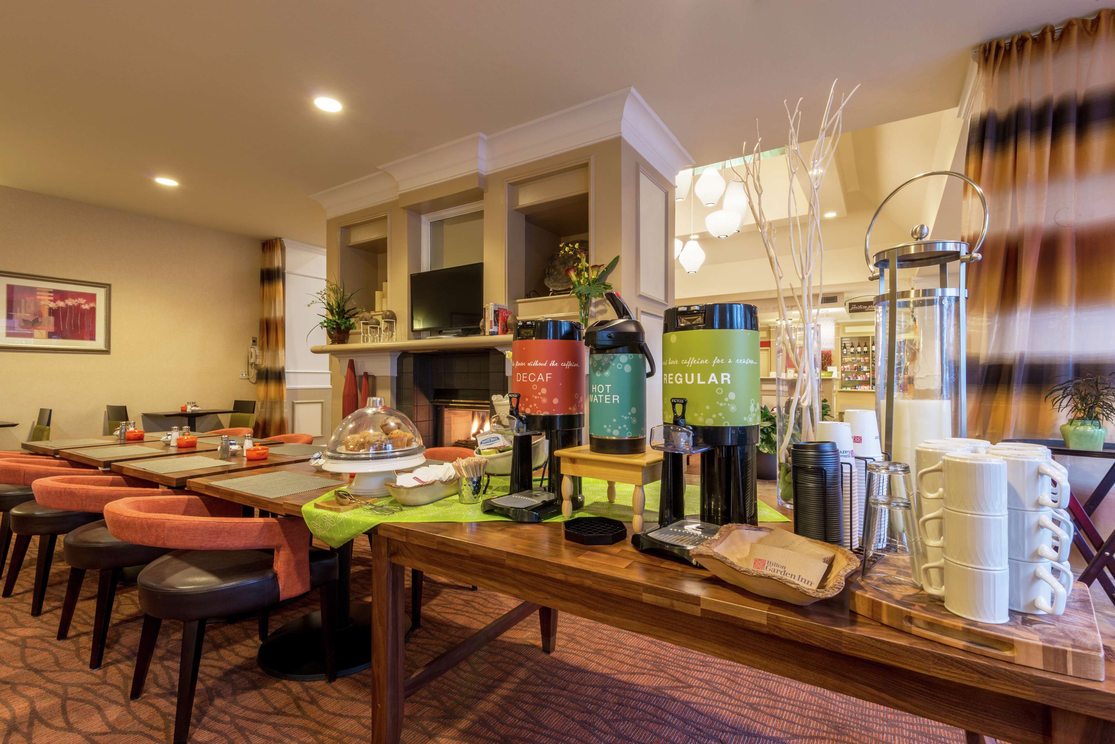 Un espace pour le petit-déjeuner à l’hôtel, doté de plusieurs coins où l’on peut se servir du café, de différents types de sièges et d’une cheminée.