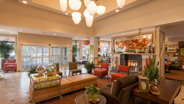 A spacious lobby with a fireplace, comfortable seating, and a large window offering a view of the outdoors. - Hilton Garden Inn - Flagstaff (Flagstaff)