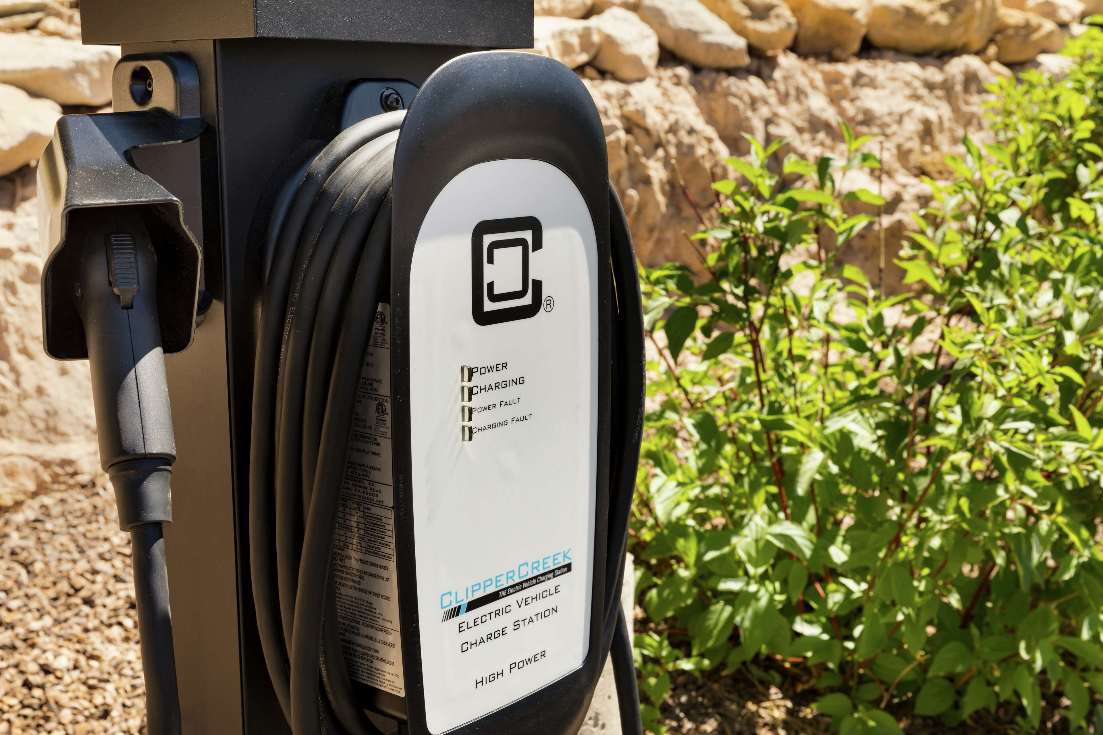 En laddstation för elfordon från ClipperCreek, med en kabel ansluten till den.