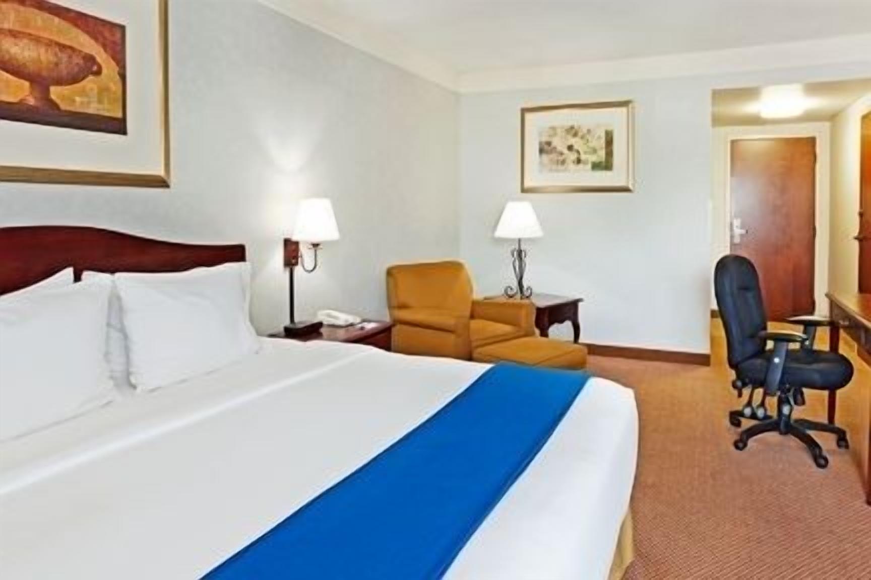 Een hotelkamer met een groot bed, een bureau, een stoel en twee lampen.