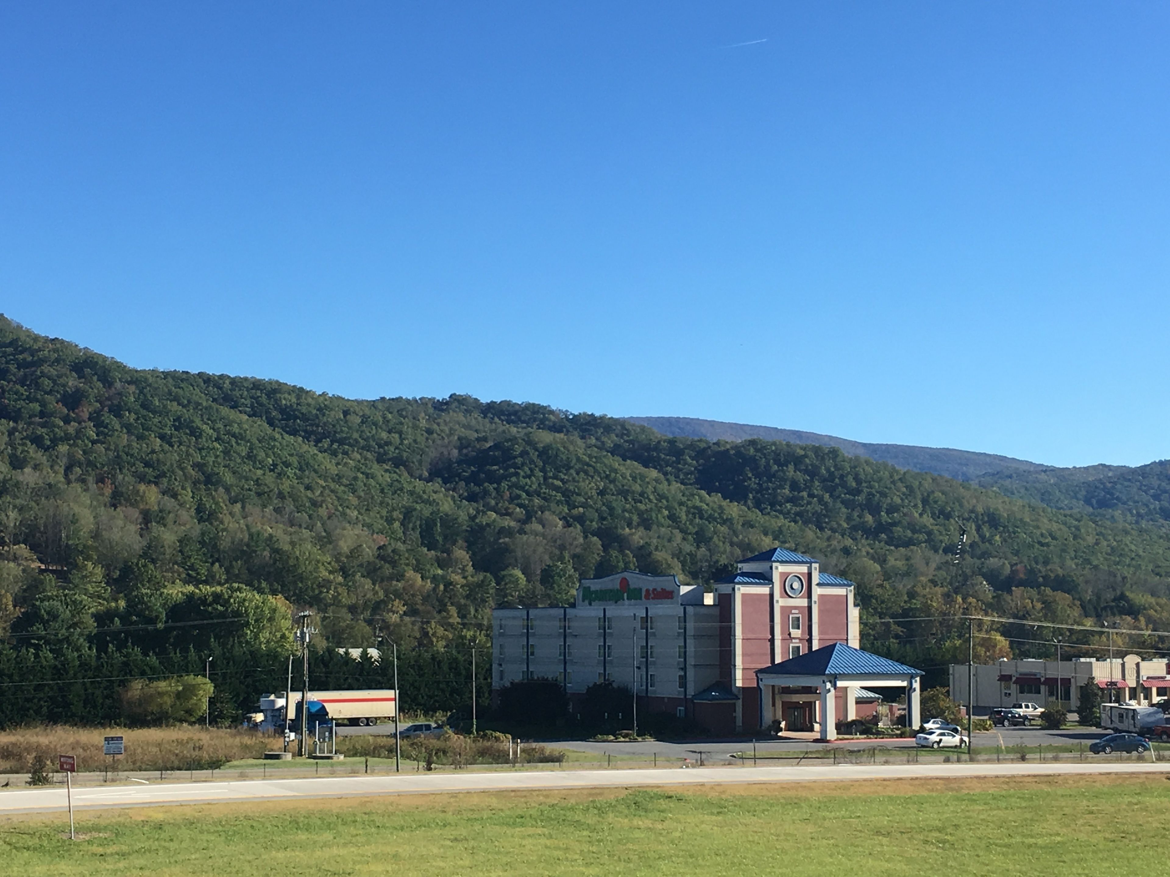 A building with a clock tower, surrounded by a parking lot and a grassy area.