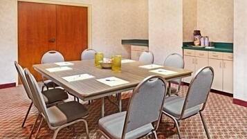 A conference room with a wooden table, six chairs, and a closed door.