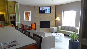 A modern living room with a television, seating, a fireplace, and a dining area. - Holiday Inn Express Kansas City-Bonner Springs by IHG (Bonner Springs)