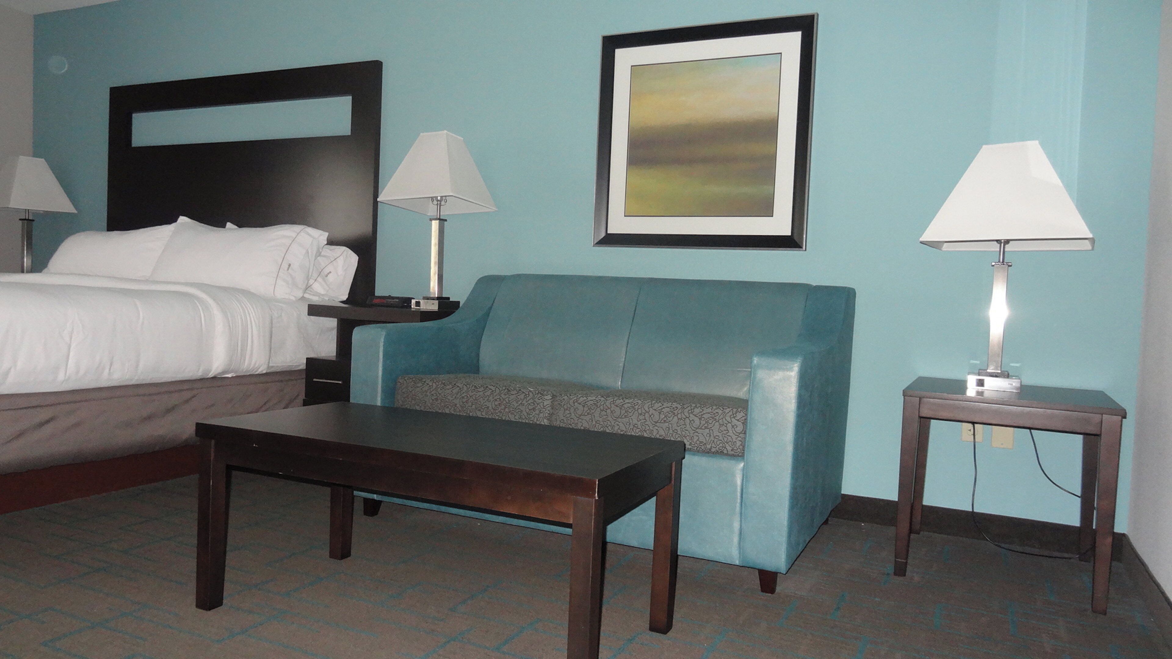 Een hotelkamer met een bed, een blauwe bank, een houten tafel en twee bedlampen.