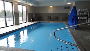 An indoor swimming pool with a no diving sign, a wooden deck, and a covered area with towels. - Holiday Inn Express Kansas City-Bonner Springs by IHG (Bonner Springs)