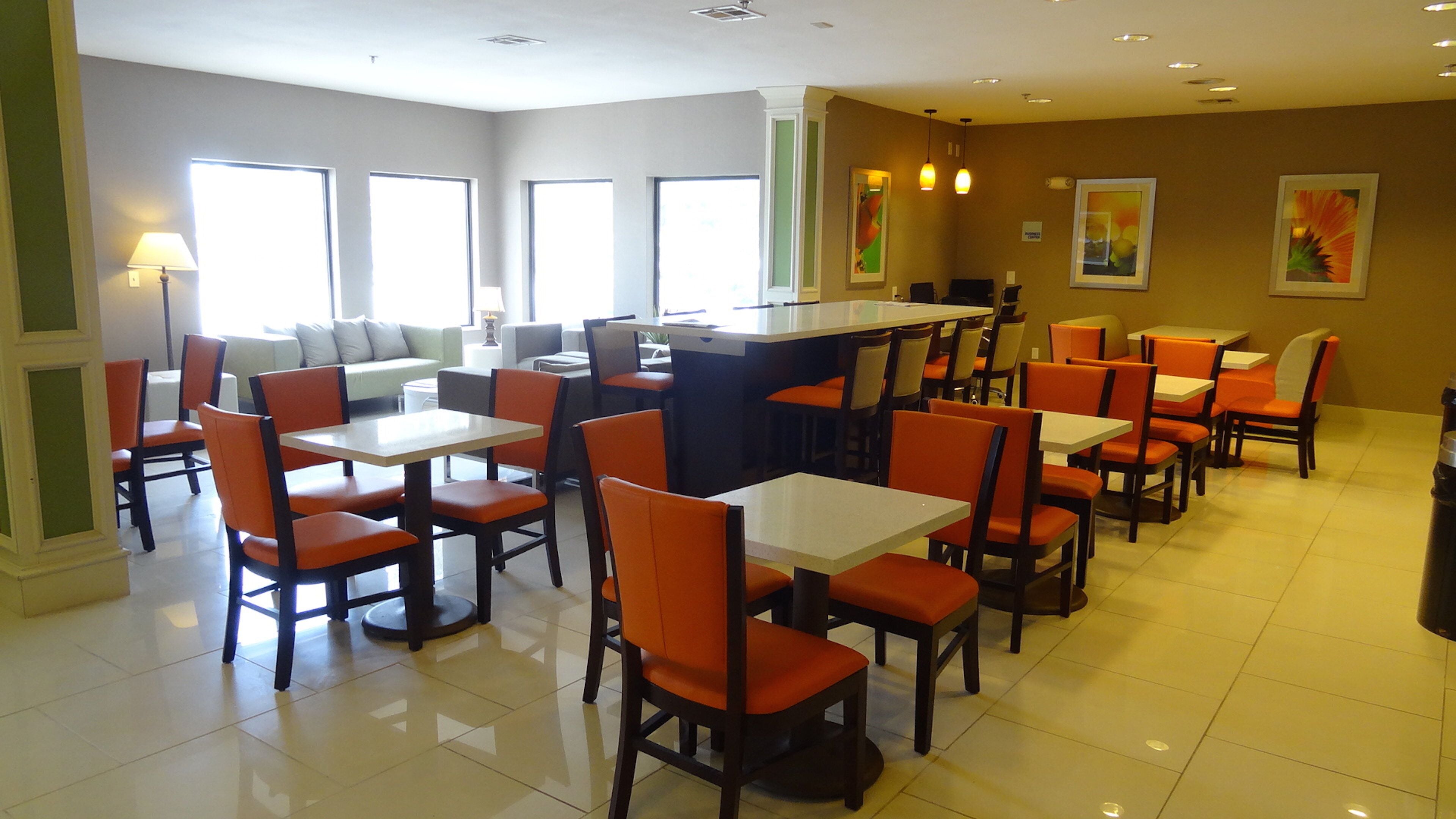 A restaurant with multiple tables and chairs, a counter, and artwork on the walls.