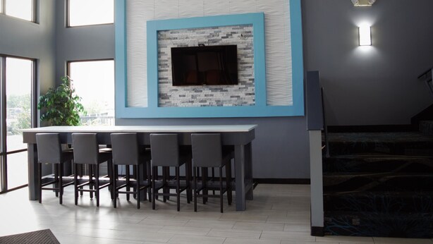 Una sala de estar moderna con chimenea de piedra, una zona de bar con sillas y ventanas amplias.