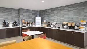 Una cocina moderna con armarios oscuros, encimera blanca y varios electrodomésticos.