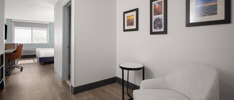 A modern hotel room with a bed, a desk, a chair, and a round table. There are three framed pictures on the wall.
