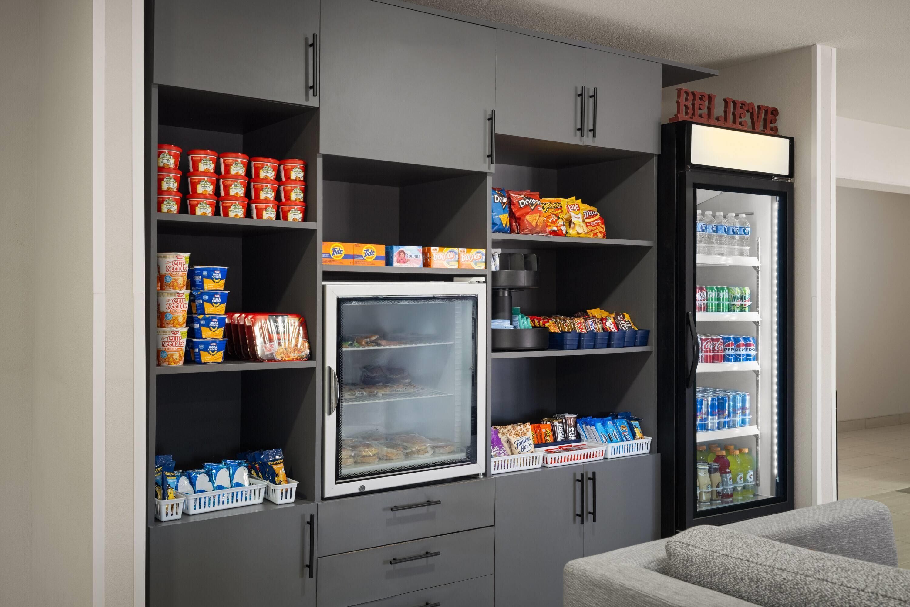 Una kitchenette equipada con refrigerador, microondas y diferentes alimentos.