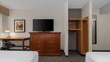 Une chambre d’hôtel avec une commode en bois, une télévision, un bureau et un lit.