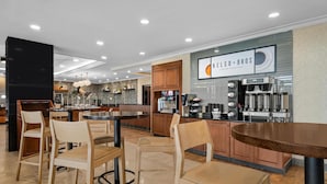 Ein modernes Café-Interieur mit Holztischen, einer Theke und einem Schild für 'KELSO+BROS Coffee Roasters'.