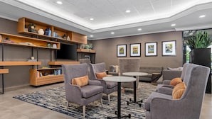Eine moderne Lounge mit grauen Sesseln, einem Sofa, einem Fernseher und einem Bücherregal.