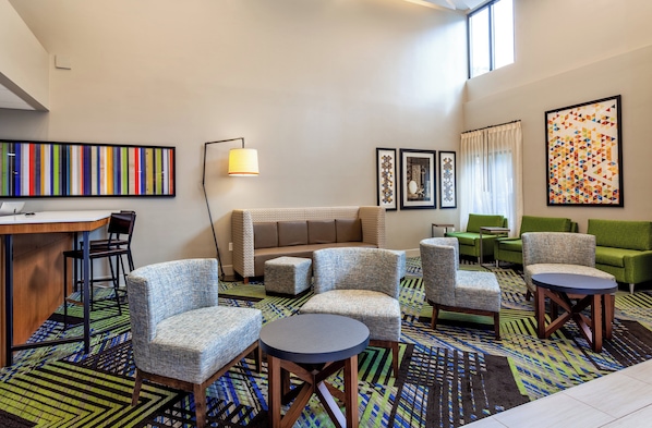 Un hall d’hôtel avec un canapé, des fauteuils, un bureau et des œuvres d’art accrochées aux murs.